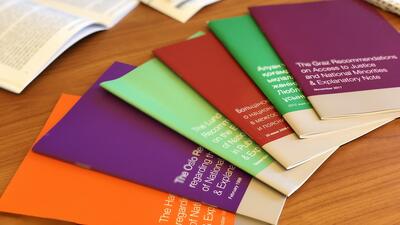 Colorful booklets with white text fanned out on a wooden table.
