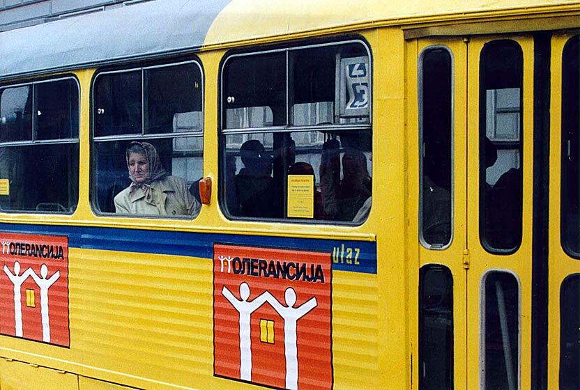 Yellow tram with posters advocating for tolerance, with passengers looking out the windows.