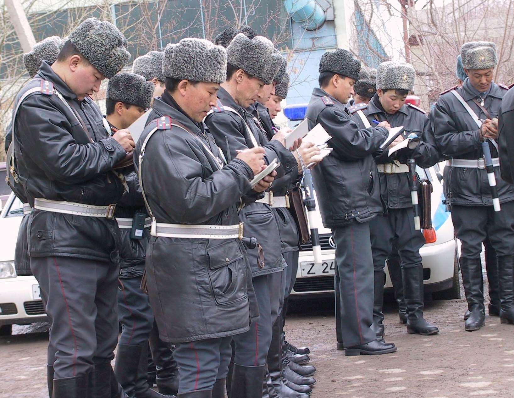 Officers in uniform, wearing fur hats, take notes outside in cold weather.